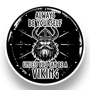 A black and white circular illustration features a bearded Viking helmet, radiating Nordic warrior energy. Text reads: Always be yourself unless you can be a Viking. This Nordic Sticker: Viking Shield is 4x4 inches, glossy, UV & water-resistant, dishwasher safe, easy peel. Buy 3 Get 1 Free.