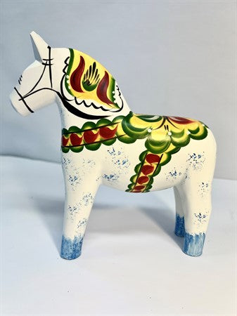The Dala Horse: Antique Inspired Swedish Dala Horse features a white hand-carved wooden body, gray feet, and colorful green, red, and yellow patterns. This 17cm figurine is inspired by the classic Swedish design.