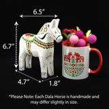 A hand-carved Dala Horse: Antique Inspired Swedish Dala Horse White with Gray Feet (17cm) stands by a mug of colorful felt flowers. Arrows show its size: 6.7" tall, 6.5" long, 1.8" wide, and 4.7" between legs. Made in Sweden.