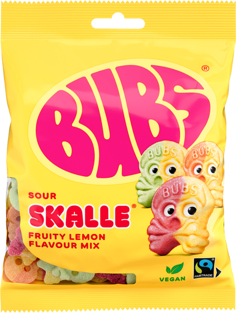A yellow 90g bag of Faire - Sweet as Fudge Candy: Bubs Sour Foam Fruity Lemon Skulls shows three cartoon lemon skull gummies, vegan and Fairtrade logos, pink BUBS branding, and Scandinavian candy pieces visible through the packaging.