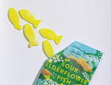 Five yellow, fish-shaped sour gummies from the Bundle: BonBon Sour 4-Pack – The Ultimate Swedish Fish Reimagined spill from a partially opened package, offering a gourmet candy twist to the classic treat on a white background.