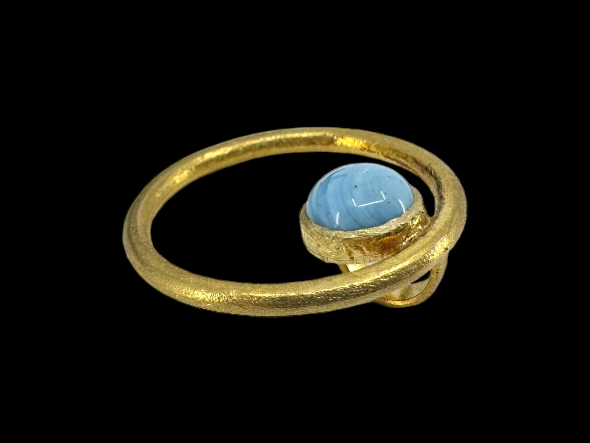 A pendant called "Cirkel Gold - Swedish Blue" showcases a round Swedish blue stone encased in a textured gold-plated setting against a black background.