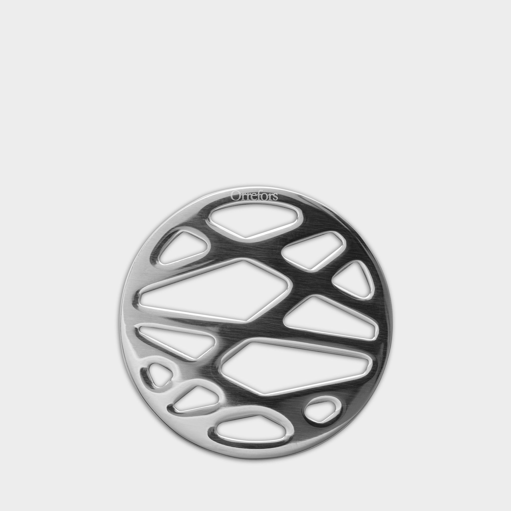 Round metallic trivet with irregular cut-outs, designed for hot dishes. Inspired by the Orrefors City Coaster (4-Pack) collection, it perfectly complements your drinkware ensemble.