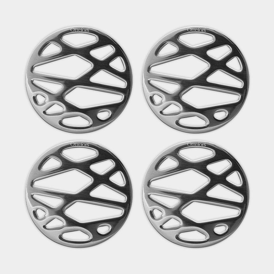 The Orrefors City Coaster 4-Pack includes four round silver coasters with intricate geometric cut-outs, arranged in a 2x2 grid. Ideal for drinkware, these coasters combine functionality with timeless elegance.