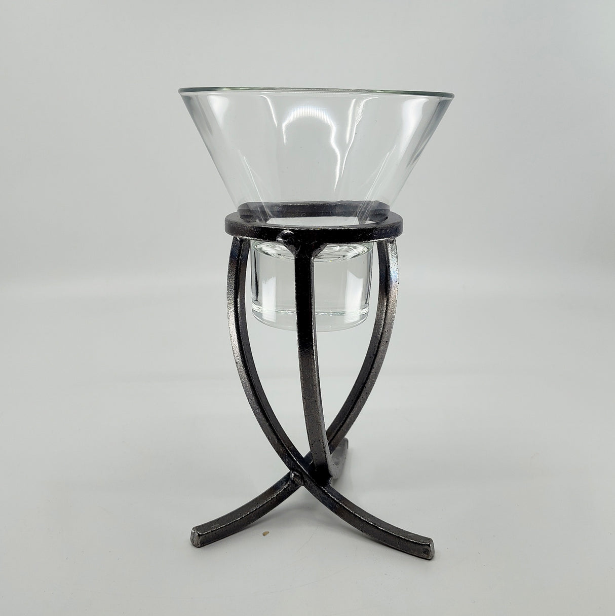 A glass Leif Cup rests elegantly on a Danish Iron Candle Holder with a crossed iron base, set against a plain white background.