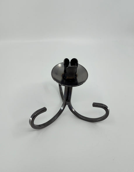 The Danish Iron Taper Candleholder, with a curly bottom and sleek black metal design, features three graceful legs and a round base, ideal for elegantly displaying tapered candles.