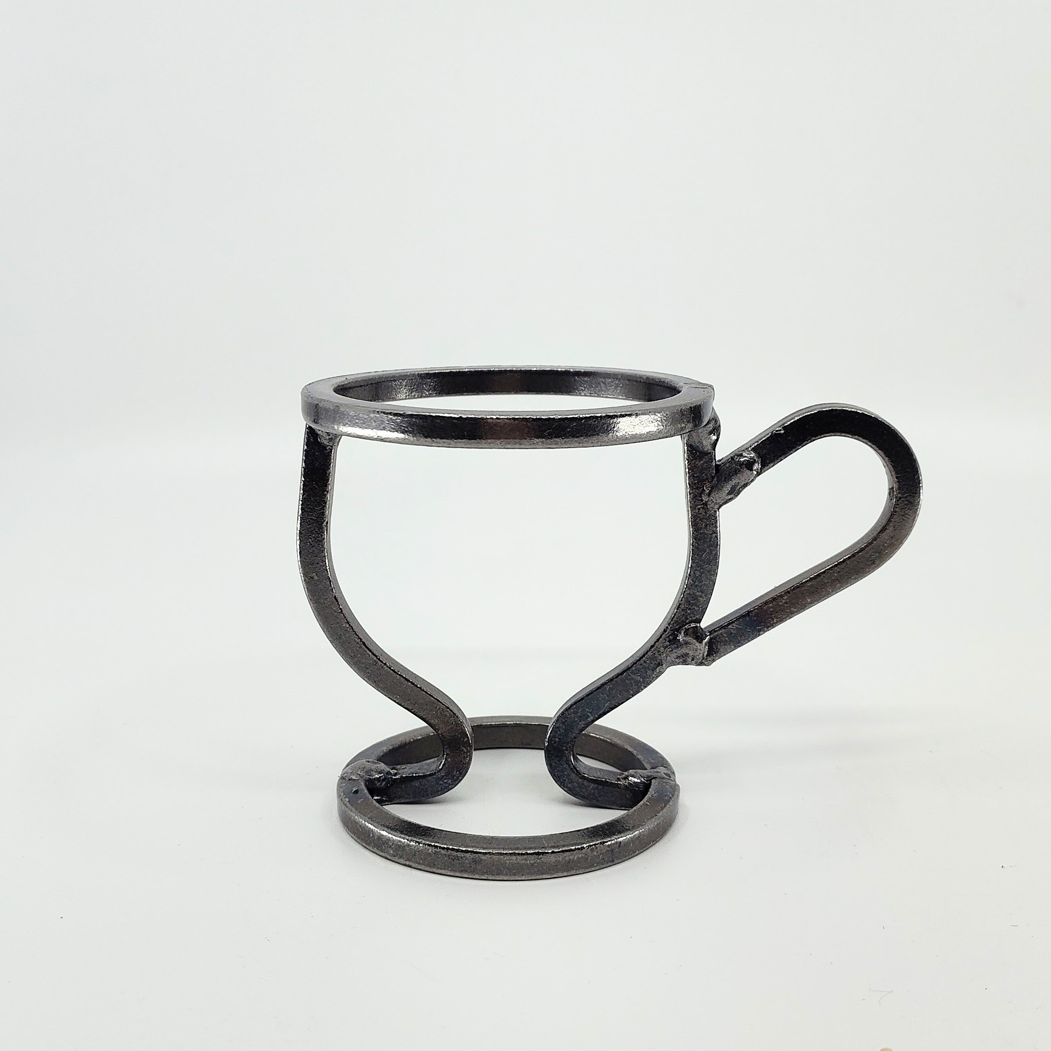 The Danish Iron Coffee Cup candle holder has a minimalistic wireframe style with a round base and handle, and includes a Leif Glass Cup for ball candles against a plain white background.