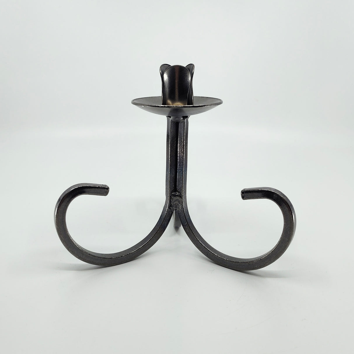 The Candle Holder: Danish Iron Taper Candleholder features a central stem with gracefully curved legs, ideal for a single taper candle.