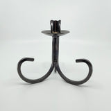 The Candle Holder: Danish Iron Taper Candleholder features a central stem with gracefully curved legs, ideal for a single taper candle.