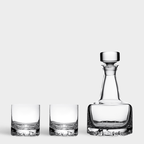 The Orrefors Erik 3-Piece Set features a 26oz clear glass decanter with stopper next to two matching 12oz double old fashioned glasses, highlighting timeless Scandinavian elegance against a plain white background.