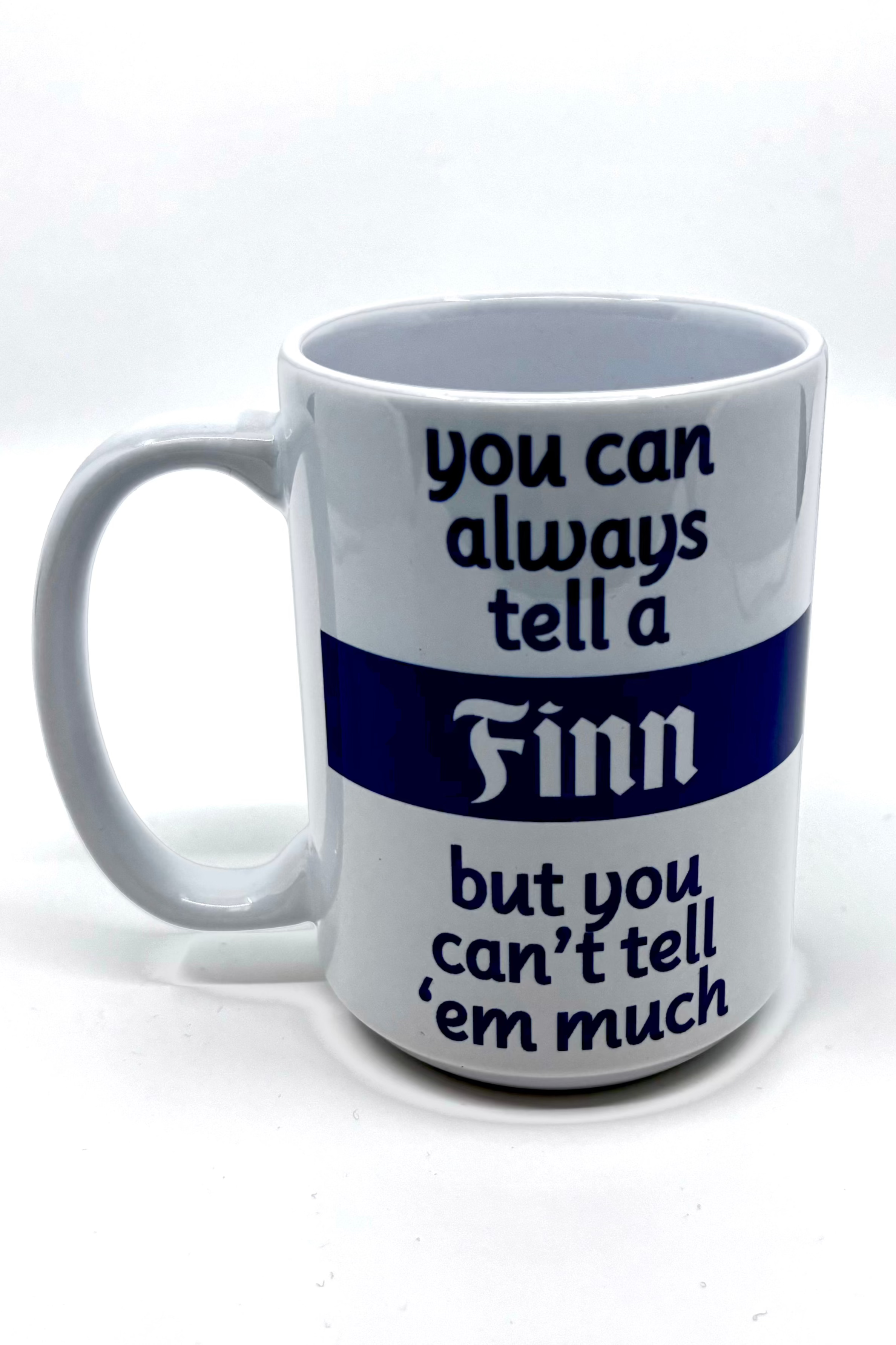 The Mug: You Can Tell a Finn is a white 15 oz mug that proudly displays the text: "you can always tell a Finn but you can’t tell ‘em much" in bold blue and black.