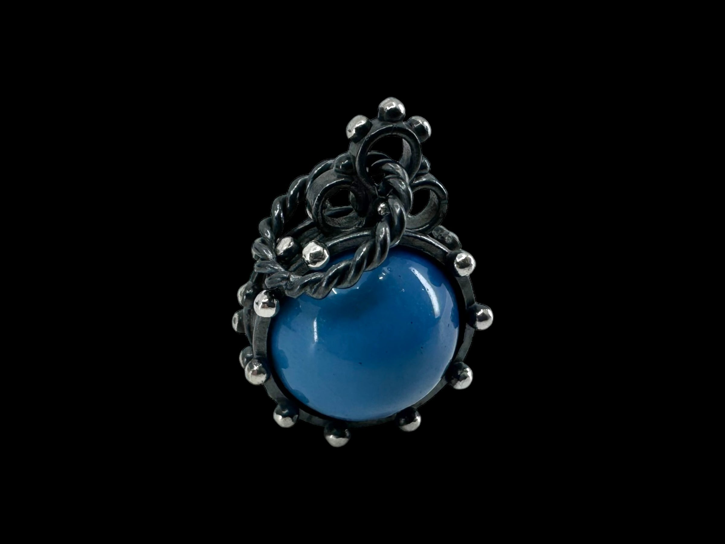 A pendant named "Freja - Swedish Blue" featuring a large, smooth Swedish Blue stone surrounded by intricate oxidized silver detailing set against a black background.