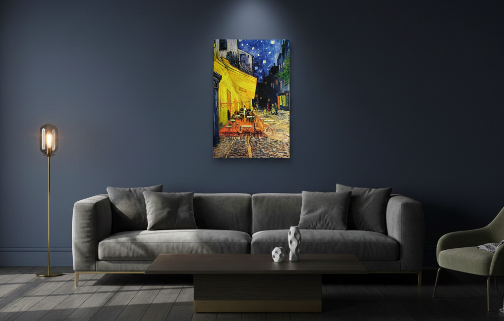 A modern living room with a grey sofa, coffee table, and the "Artwork: Café Terrace at Night Vincent Van Gogh 1853 - 1890 Print on Canvas" wall-mounted and illuminated by a spotlight.