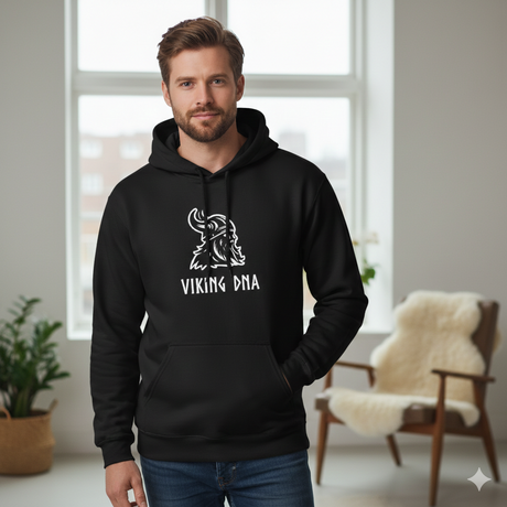 A bearded man stands indoors wearing the black Hoodie: Nordic Viking DNA Heritage Sweatshirt with Hood, which features a Viking helmet graphic and "VIKING DNA" text, proudly displaying his Nordic heritage.