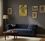 A navy blue sofa sits against a gray wall featuring the Sunflowers Vincent Van Gogh 1853–1890 Print on Canvas; in front is a round wooden coffee table with books and an orchid.