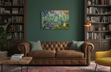 A brown leather tufted sofa with two green pillows sits against a dark green wall, beneath bookshelves and an Irises Vincent Van Gogh 1853-1890 print on canvas. A colorful oil painting and floor lamp add to the cozy atmosphere.
