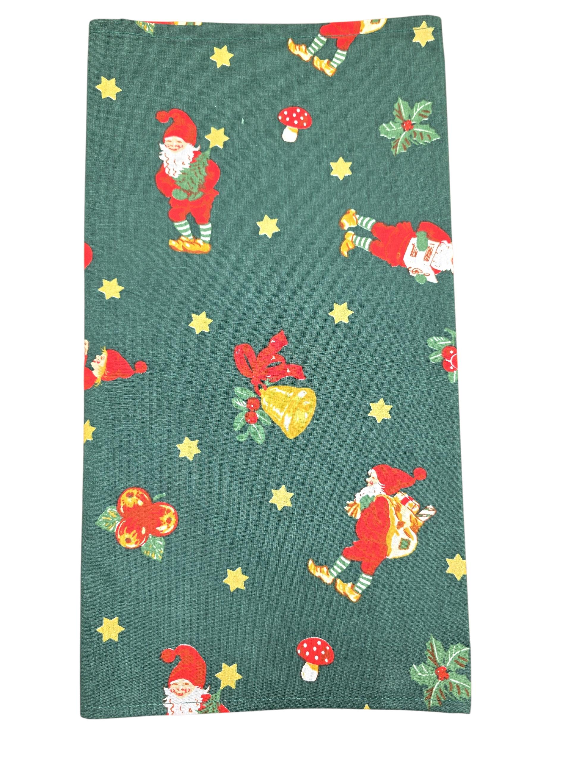 The "Jultomtar" Christmas Gnome or Santa table runner (48" long) features green fabric with Santa figures, yellow stars, bells, holly leaves, red mushrooms, and ornaments—ideal for a folk-art inspired Swedish holiday table.
