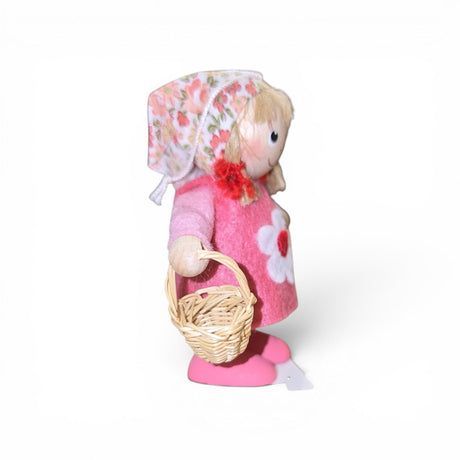 The Faire - Nordic Dreams Figurine: Scandinavian Tomte Girl in Pink features a blonde gnome with a pink floral headscarf, dress, and shoes, holding a woven basket—perfect Nordic decor made in Scandinavia.