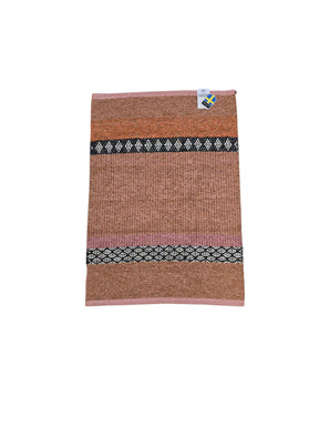The Horredsmattan Forest Rust cotton/vinyl rug features brown, pink, and black geometric patterns and a small tag at the top right corner.