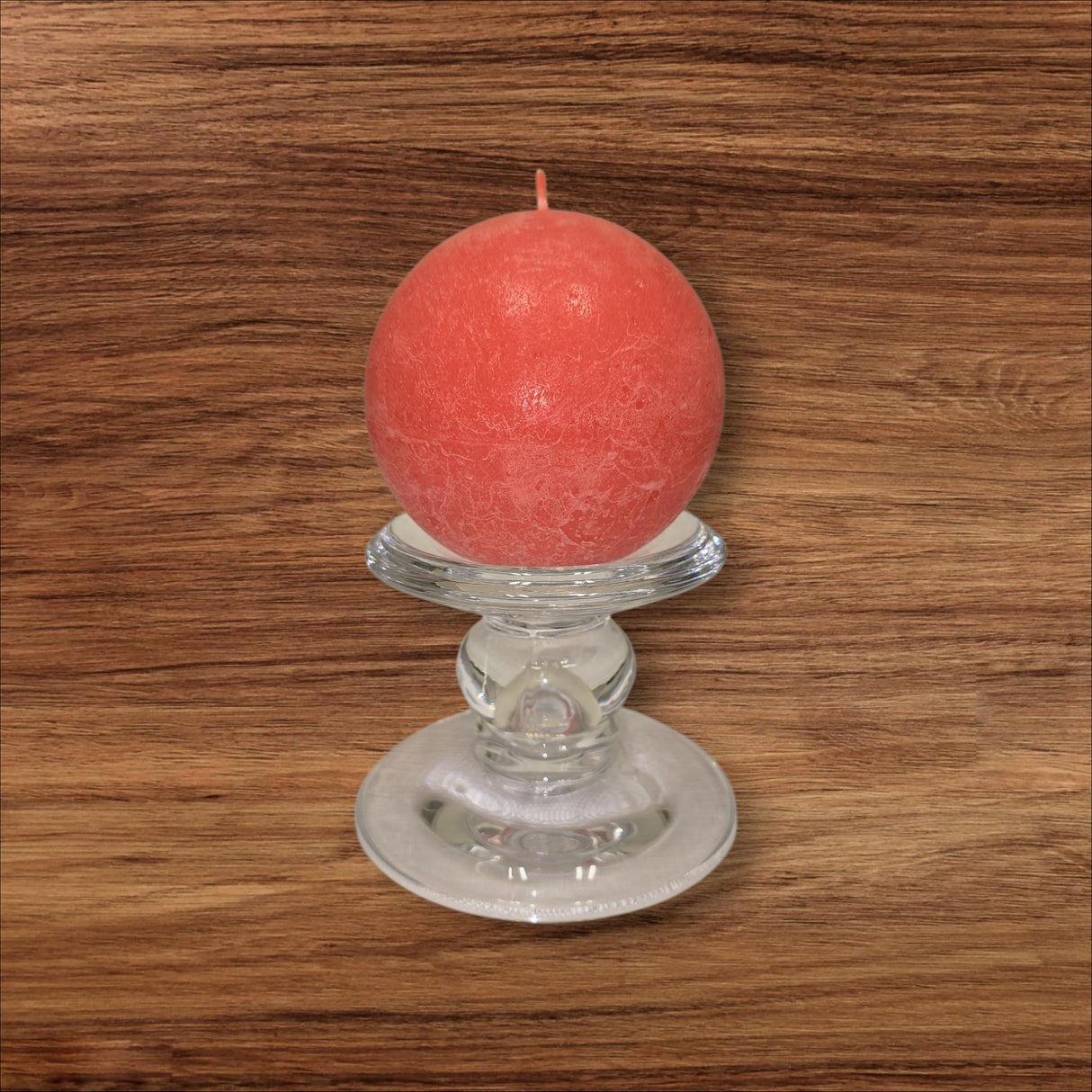 A round red candle rests on the Glass Dual-Size Reversible Candle Holder, designed for taper, ball, or pillar candles, displayed on a wood surface with visible grain.