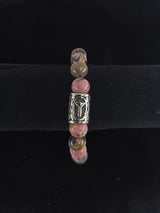 Beaded bracelet with pink, brown, and clear round beads and a central silver bead engraved with the Algiz rune, shown on a black velvet display stand.