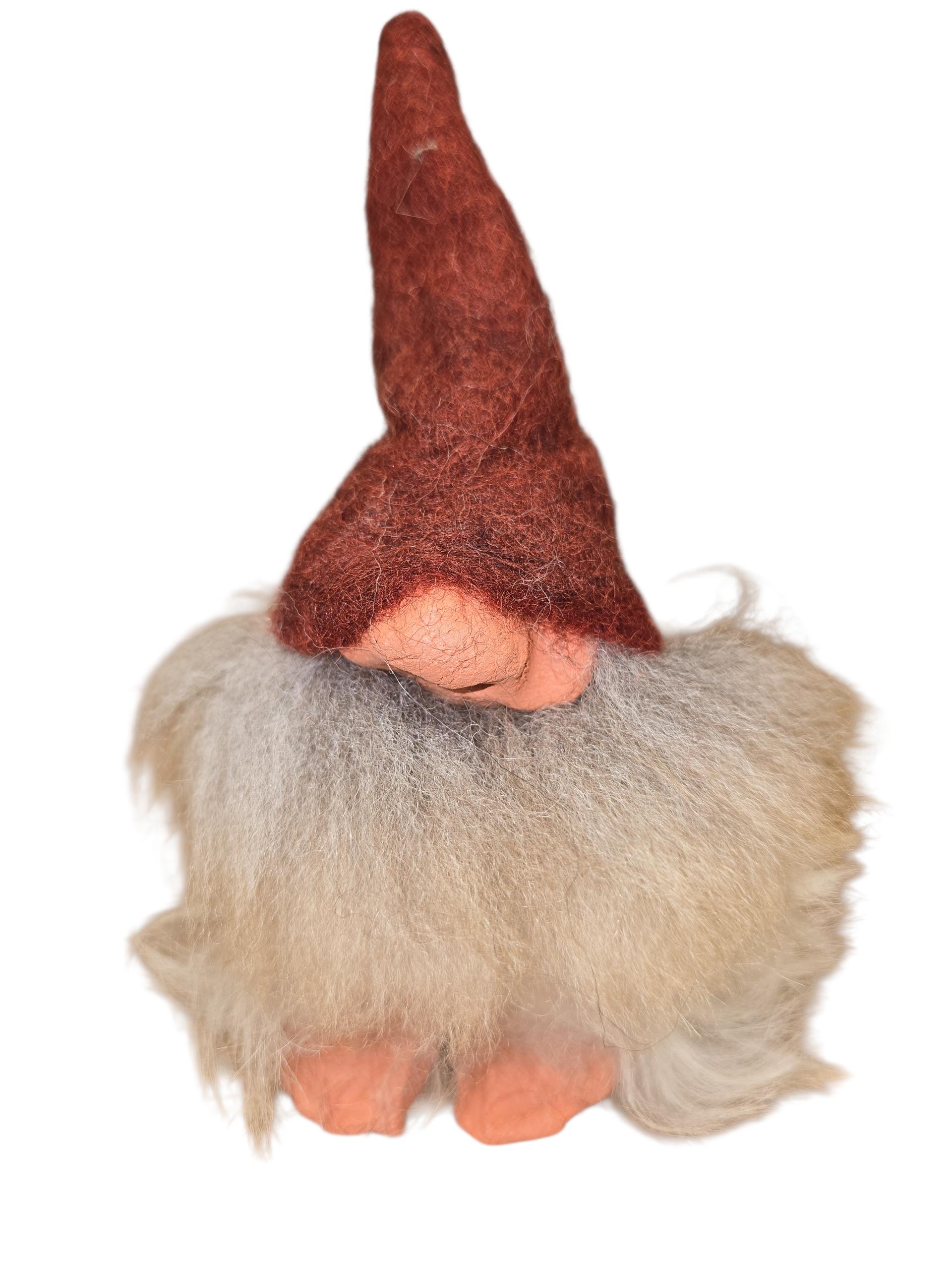 The "Foot Tomte" is a 6" handcrafted Swedish gnome by Gumselids, featuring a tall red hat, large white and gray sheep’s wool beard, clay nose and feet, and no visible eyes or mouth.