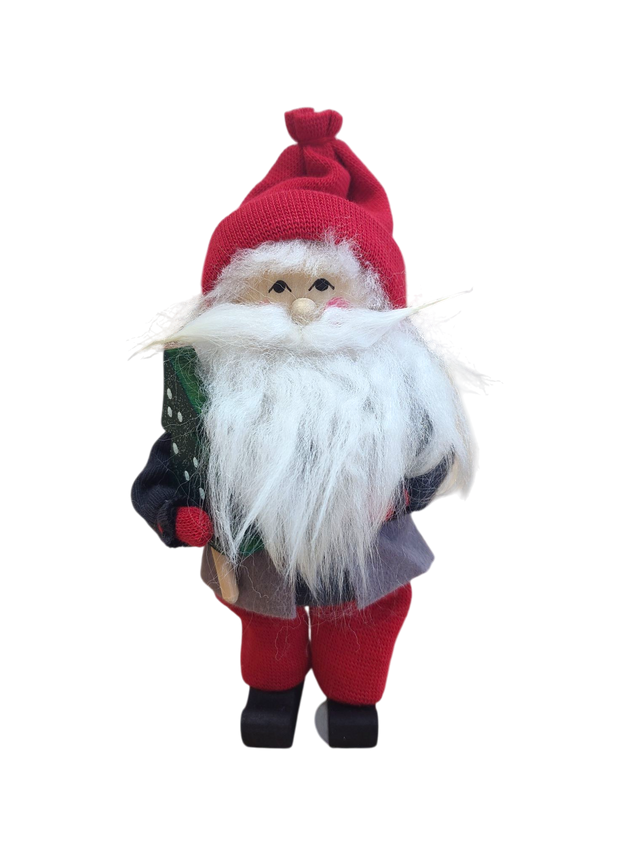 The Figurine: Santa with Glittering Tree is a handcrafted Swedish Santa with a red hat, bushy white beard, and red pants, holding a glittering green tree, set against a white background.