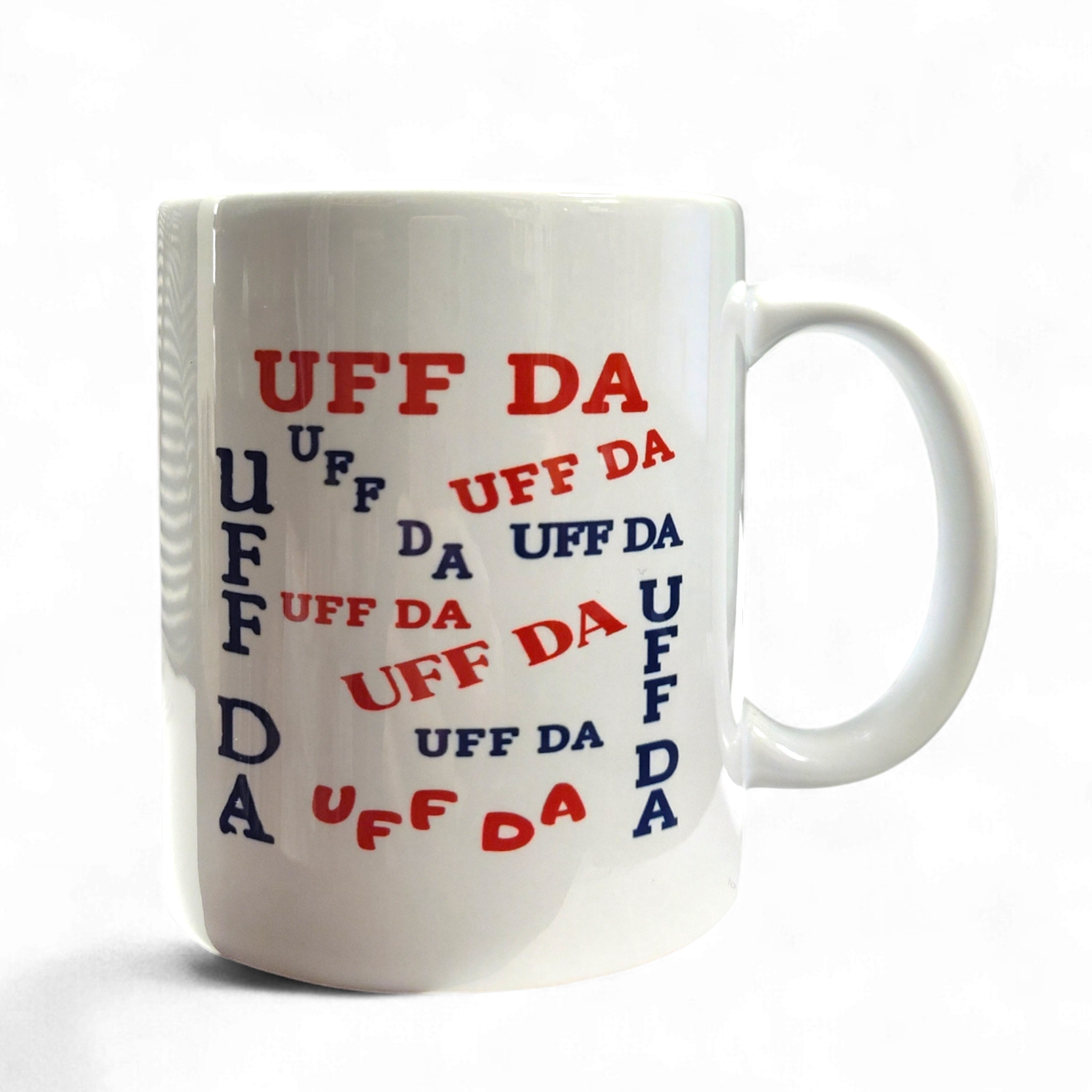 The 11oz "Uff Da" Mug features the phrase in bold red and blue prints, creating a playful Nordic design—ideal for anyone who enjoys classic Scandinavian style with a whimsical touch.