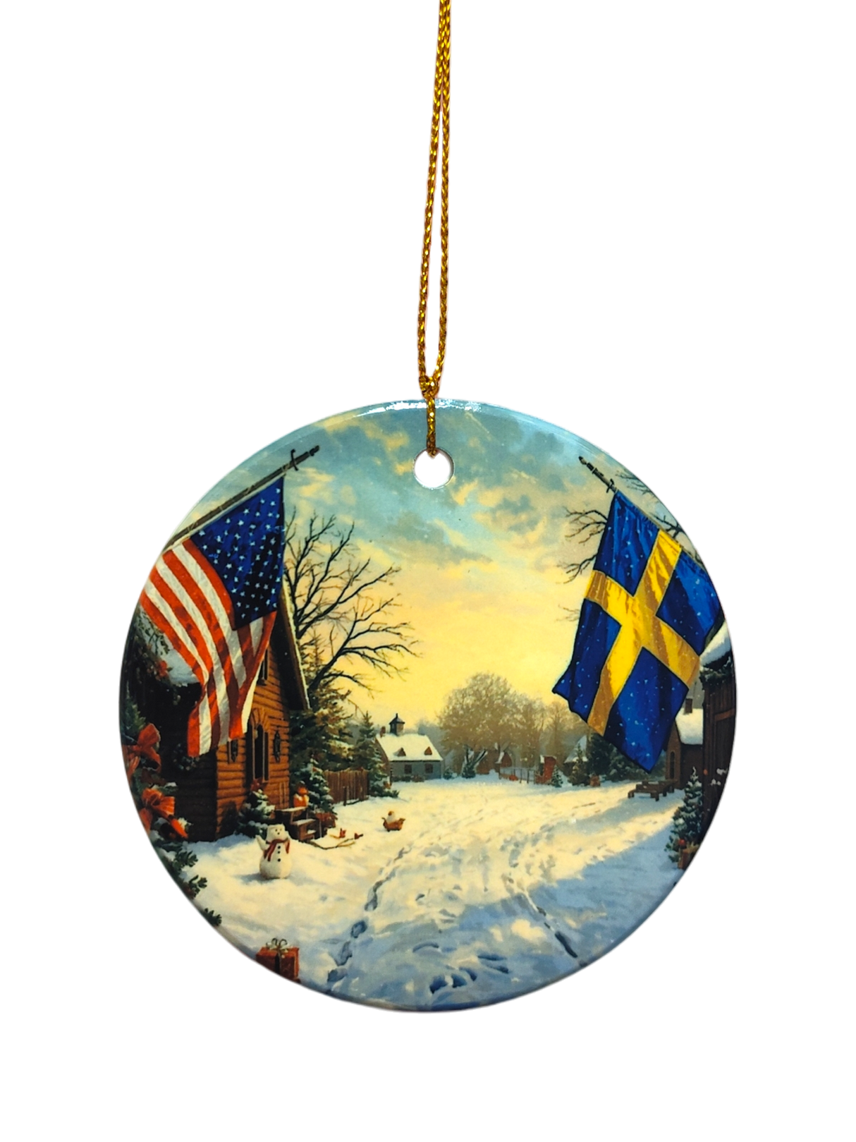 The Ornament: Wooden Village Ceramic Ornament with USA & Sweden Flags features a snowy village scene and hangs from a gold string—ideal for Scandinavian Christmas décor.