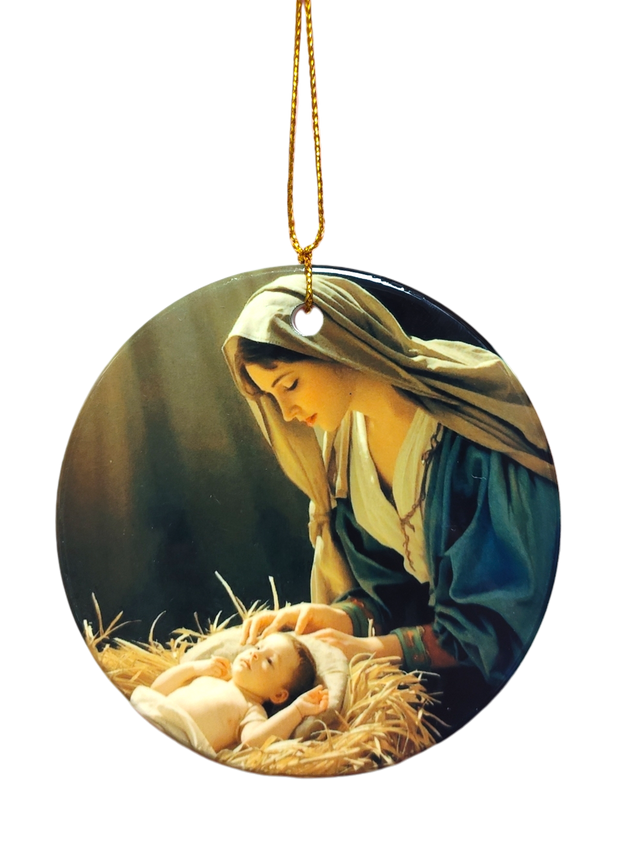 The Ornament: Nativity Scene Ceramic Ornament features a painting of a woman in a headscarf gazing at an infant on straw, with a gold hanging string—an elegant faith-inspired Christmas décor piece.