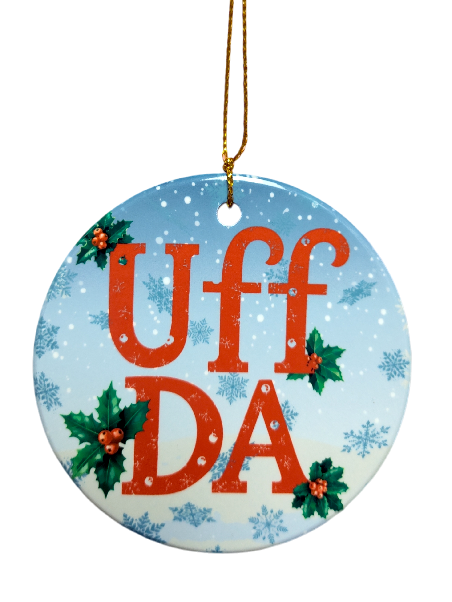 The Ornament: Uff Da Ceramic Ornament features "UFF DA" in red, holly leaves and berries, blue snowflake background, and a gold hanging string—a charming Scandinavian holiday décor piece.