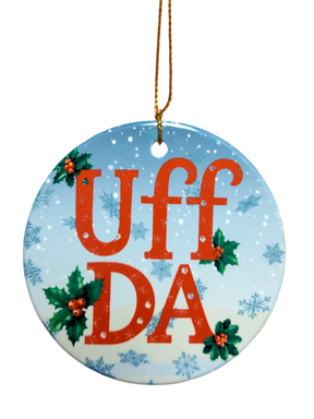 The Ornament: Uff Da Ceramic Ornament features "UFF DA" in red, holly leaves and berries, blue snowflake background, and a gold hanging string—a charming Scandinavian holiday décor piece.