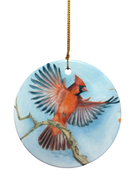 Ornament: Red Cardinal Ceramic Ornament with a painted cardinal in flight above a branch and gold hanging string. A charming gift for bird lovers.