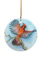 Ornament: Red Cardinal Ceramic Ornament with a painted cardinal in flight above a branch and gold hanging string. A charming gift for bird lovers.