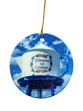 The Ornament: Valkommen till Lindstrom Ceramic Ornament features a water tower painted as a teapot with “Välkommen till Lindström” in Swedish, celebrating the city's Scandinavian heritage against a blue sky.