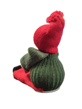 The Figurine: Handcrafted Swedish Santa Boy Sitting with Red Dala Horse features a green body, red hat and scarf, capturing classic Swedish Christmas decor. Photographed against a white background.