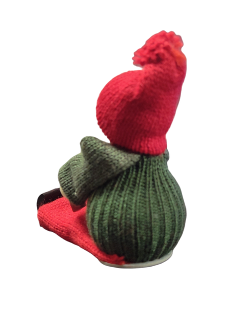 The Figurine: Handcrafted Swedish Santa Boy Sitting with Red Dala Horse features a green body, red hat and scarf, capturing classic Swedish Christmas decor. Photographed against a white background.