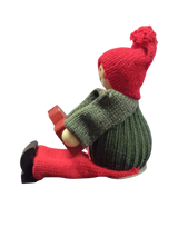 A handcrafted Swedish Santa boy figurine sits holding a red Dala horse, dressed in festive attire—a charming piece of Swedish Christmas decor.