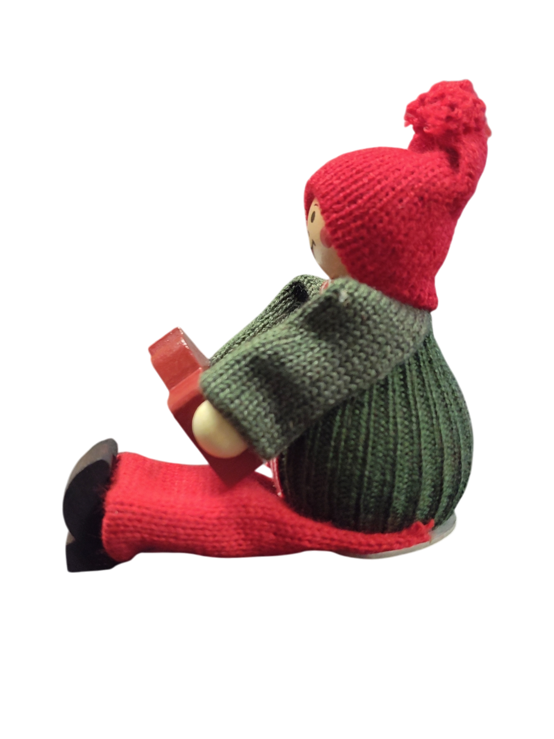 A handcrafted Swedish Santa boy figurine sits holding a red Dala horse, dressed in festive attire—a charming piece of Swedish Christmas decor.