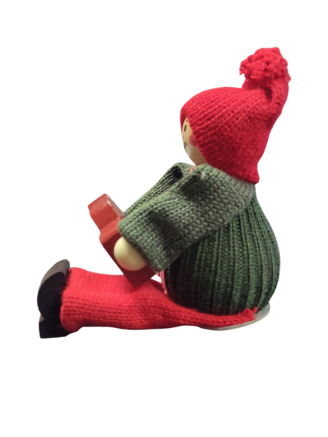 A handcrafted Swedish Santa boy figurine sits holding a red Dala horse, dressed in festive attire—a charming piece of Swedish Christmas decor.