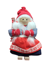 The Figurine: Santa Girl in Traditional Holiday Dress Carrying a Candy-Cane Striped Package features a handcrafted Swedish design—white hair, red mittens and hat, blue and red dress—a charming addition to your Scandinavian Christmas décor.