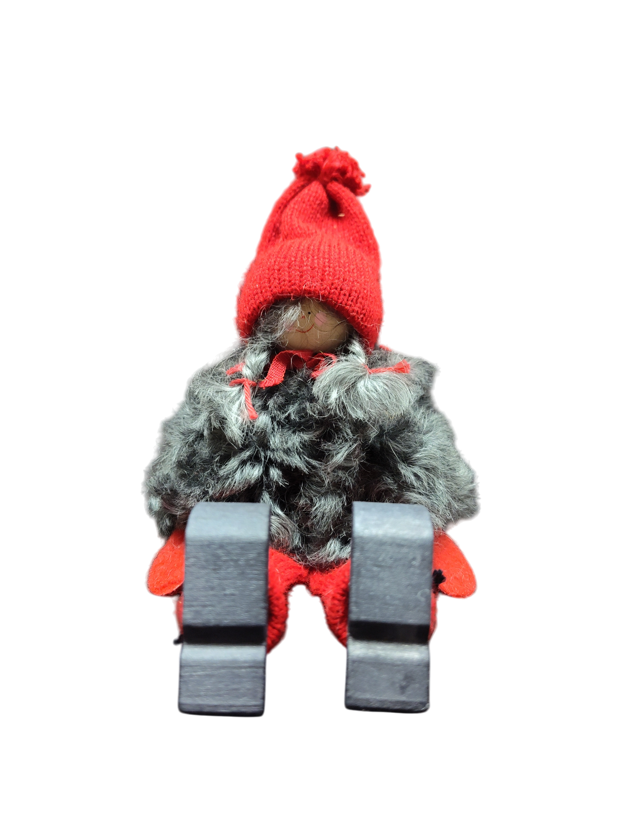 The Sitting Santa Girl Figurine features a red knit hat, mittens, gray faux fur coat, red pants, and black boots. Displayed upright against a white background, it makes a charming addition to your Christmas décor.