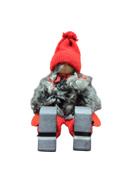 The Sitting Santa Girl Figurine features a red knit hat, mittens, gray faux fur coat, red pants, and black boots. Displayed upright against a white background, it makes a charming addition to your Christmas décor.