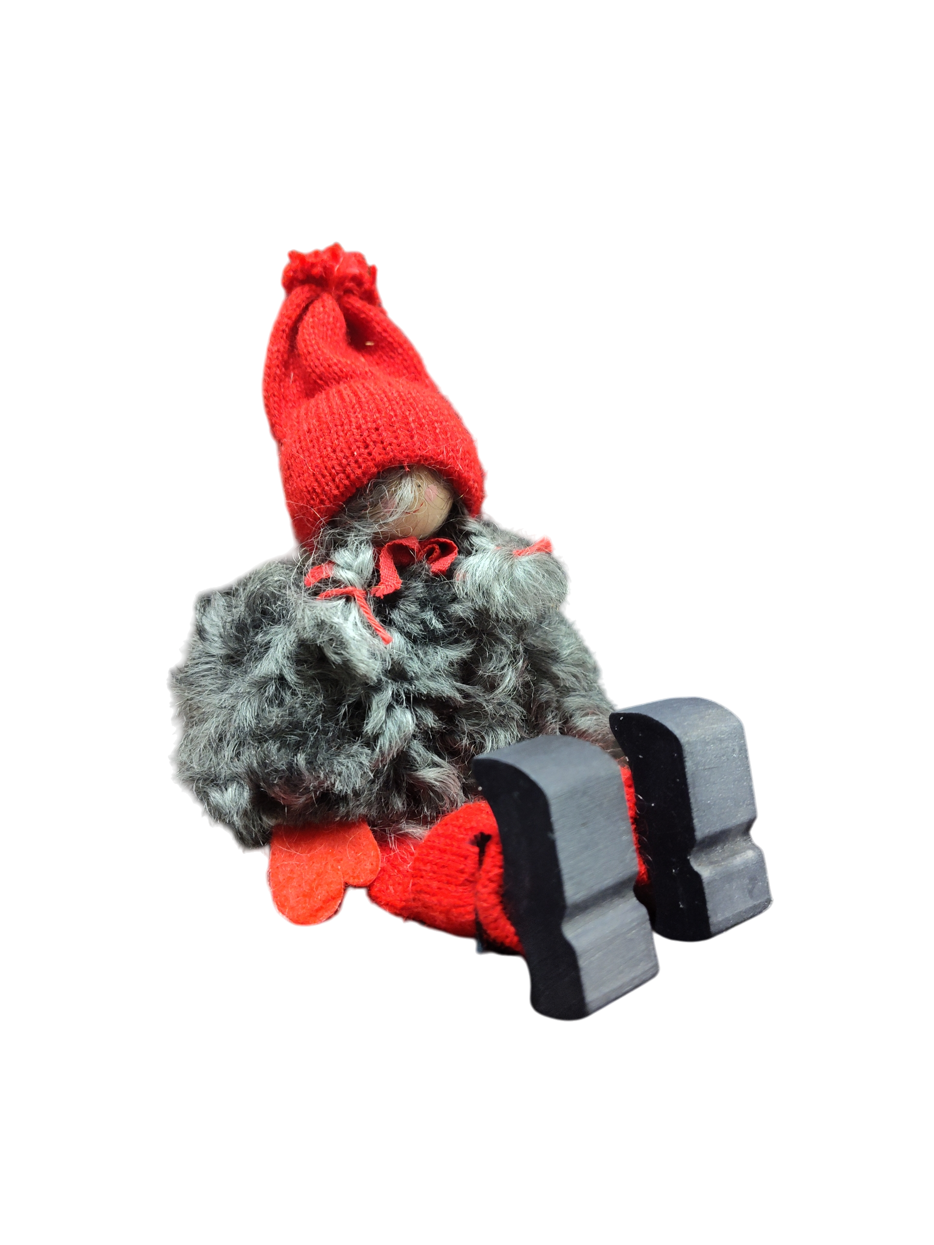 The Sitting Santa Girl Figurine features a red knit hat, red mittens, gray fuzzy coat, and black wooden shoes—handmade in Sweden and perfect as charming Christmas décor.