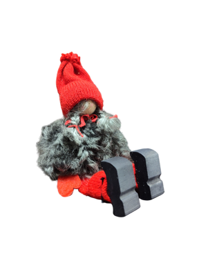 The Sitting Santa Girl Figurine features a red knit hat, red mittens, gray fuzzy coat, and black wooden shoes—handmade in Sweden and perfect as charming Christmas décor.