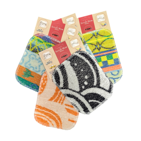 Four vibrant Scrub: Kitchen Scrubber Scrub-Wow pads in assorted patterns and packaging, overlapping on a white background. Safe for Teflon cookware and easy to clean.