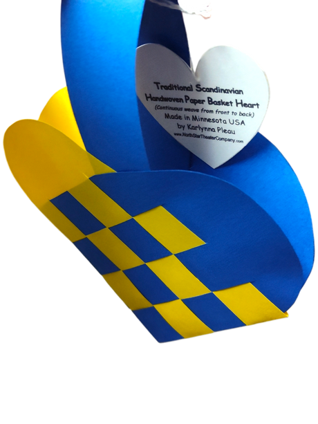 A Scandinavian heart basket in blue and yellow with a woven design, featuring a white heart-shaped tag. Product name: Card: Swedish Flag Traditional Scandinavian Handwoven Paper Basket Heart.