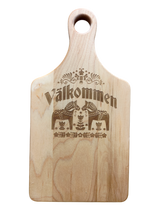 Maple wood cutting board (13.5" x 7") with handle, engraved Swedish folk art design, and “Valkommen” (Welcome in Swedish) at the center.