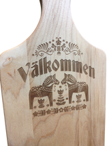 The "Valkommen" Maple Wood Cutting Board (13.5" x 7") features the Swedish word for welcome, two Dala horses, and detailed floral patterns inspired by Swedish folk art.
