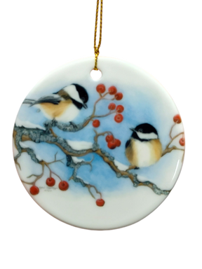 The Ornament: Winter Chickadees Ceramic Ornament features two chickadees on snowy branches with red berries, accented by a gold hanging string—a delightful bird-themed Christmas decoration for your tree.